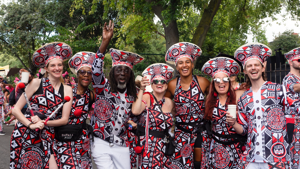 Batala London members celebrating together in red, black and white Carnival costume