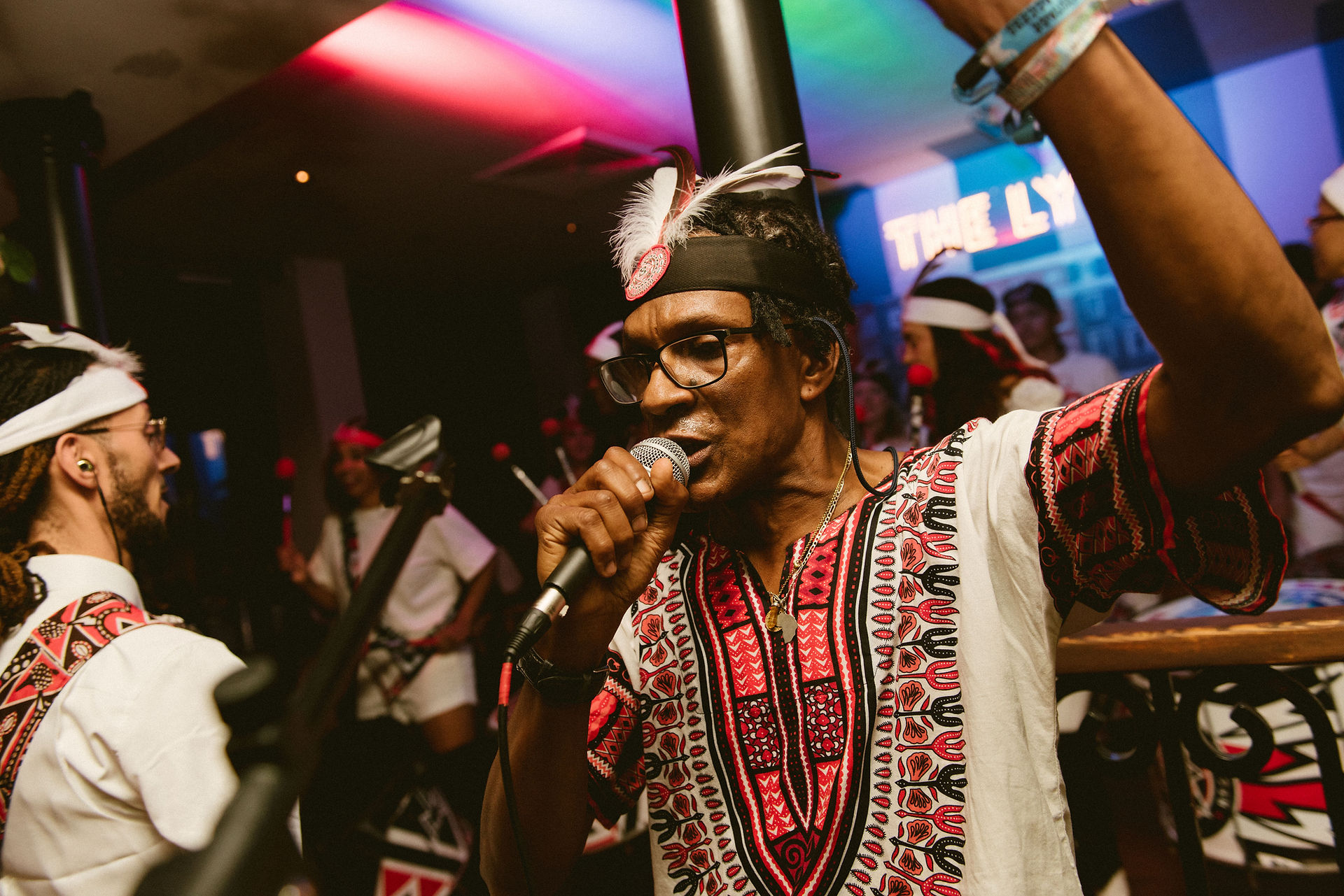 Man in feathered headband singing into microphone