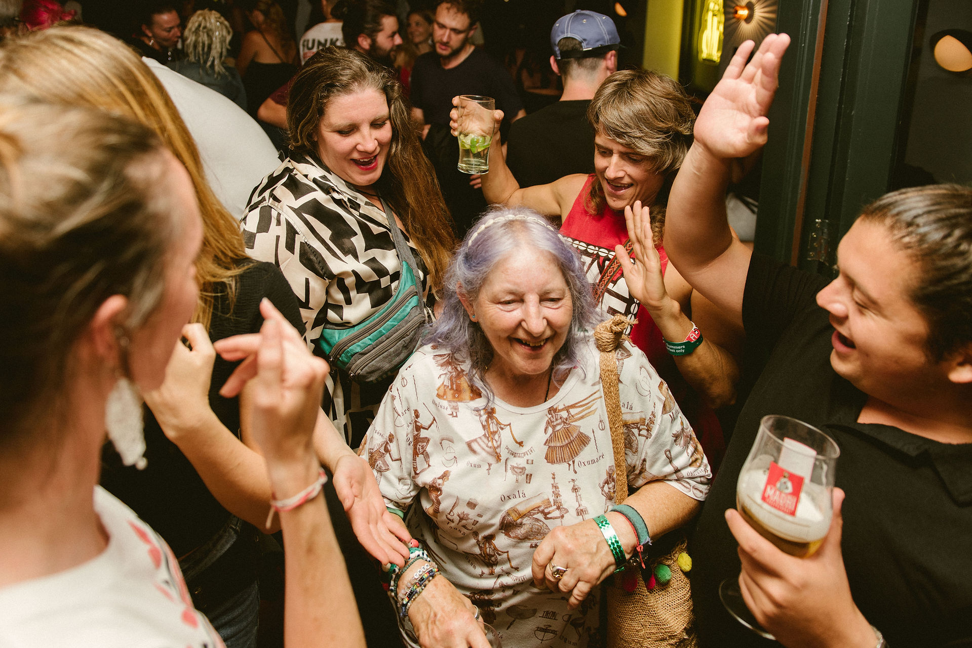 Smiling older woman dancing with people in a crowded room