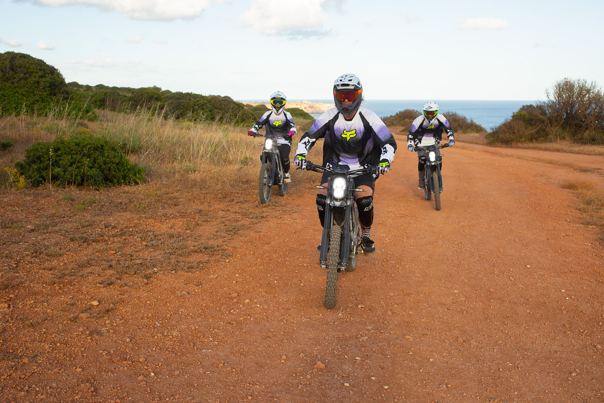 three people riding surrons on a cliff
