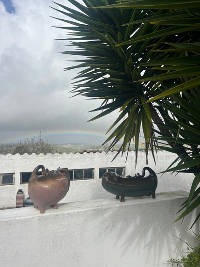 a white wall with ceramic bull sculptures facing eac other and cloudy sky with a rainbow