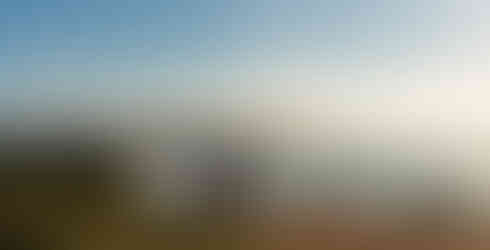 motocross rider facing camera riding on a cliff with. blue ocean and sky behind