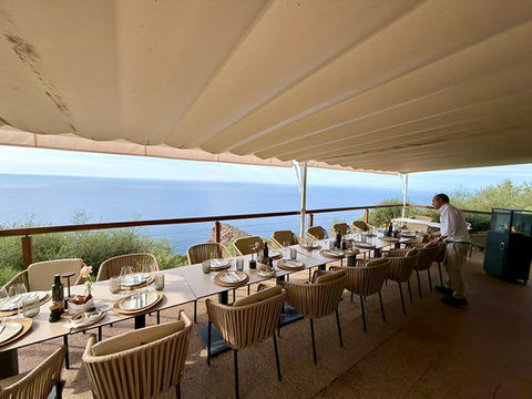Long outdoor dining table with chairs and ocean view