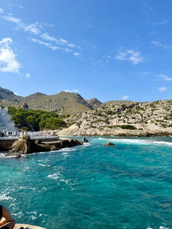 Coastal view with turquoise sea, white buildings, and rocky hills