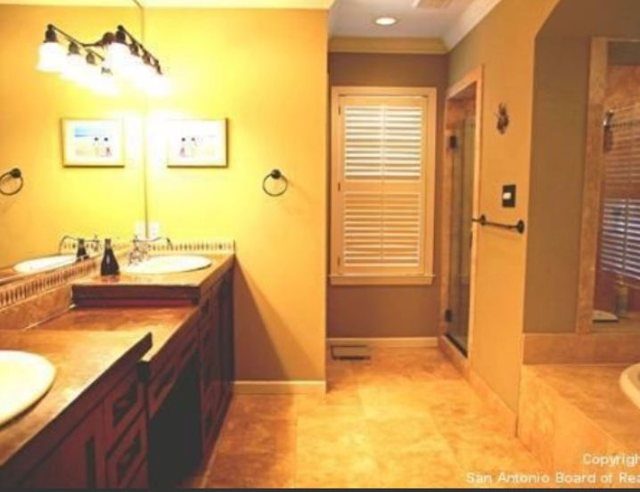 Fun turquoise primary bath, with Mexican encaustic patterned tile, white subway tiled walls, heavy glass, open corner shower, large beveled glass mirrors, quartz countertops, crystal chandelier, blue walls, pineapple lighting sconces, dark shaker style cabinetry, French champagne plumbing fixtures