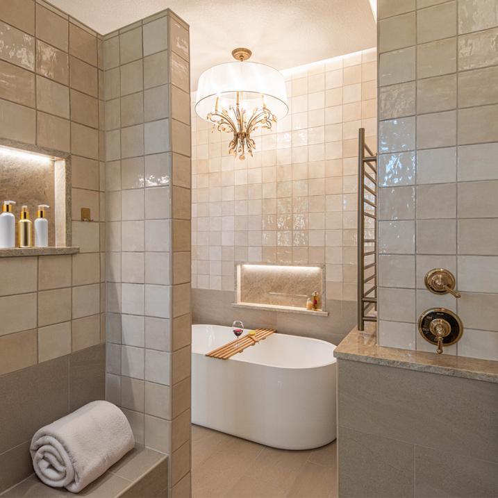 Beautiful monochromatic, soft warm neutral primary bath. Soaker tub. "Zellige" look wall tiles. Large formate tiles. Towel warmer. Lighted shampoo niches. Taj Mahal shelves. Crystal and silk shade chandelier. Kohler Artifacts fixtures. Elegant primary bath.
