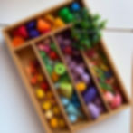 Wooden tray filled with coloured loose parts for play