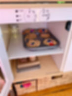 Kids imaginative play using chickpeas and jewels for pretend cooking in a kids play kitchen oven.