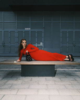 a woman in a red dress is laying on a bench in front of a building with the number 55 14613 on it