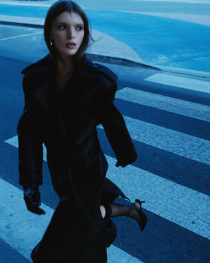 a woman in a black coat is crossing a street