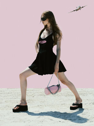 a woman in a black dress is holding a pink purse