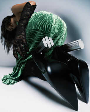 a woman in a green dress and black gloves is kneeling down