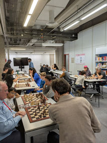 Chess lesson area with display screen and long rows of boards at the Cité des sciences ChessMates event.