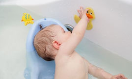 Neonato durante il bagnetto che gioca con un anatroccolo, momento perfetto per pulire le orecchie neonato in modo sicuro e naturale