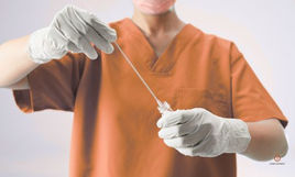 Ostetrica con guanti e scrub terracotta mostra un tampone vaginale sterile in ambulatorio