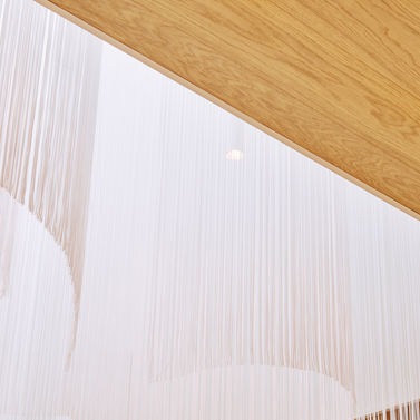 Interiorfotografie weiße Designerlampe mit künstlerischem Fadenspiel im Foyer eines Hotels