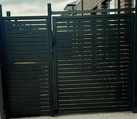 Modern black slat gate installed on concrete driveway