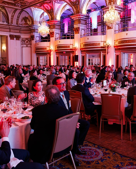 Guests enjoying a formal dinner in a grand ballroom with elegant chandeliers at the Japan Society of Boston Gala Dinner.