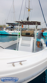 El capitán de Windward Catch limpiando la cubierta del barco blanco tras finalizar una jornada de pesca en el puerto de Tenerife.