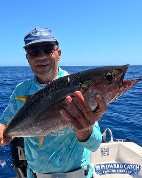 Fotografía vertical del capitán mostrando con orgullo un atún rabil capturado a bordo del barco Windward Catch Fishing Charter en Tenerife.