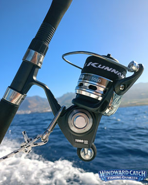 Primer plano de un carrete de spinning profesional fijado en la borda del barco Windward Catch Fishing Charter navegando por el mar.
