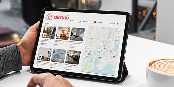 Businessman using airbnb app on tablet in cafe