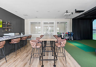 Modern indoor golf simulator room with bar and seating