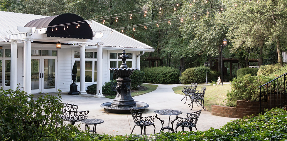 Outdoor patio with fountain, cafe seating, and string lights