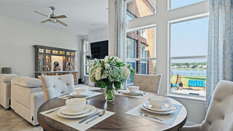 Dining room setup with round table, flowers, and a beautiful outdoor view.