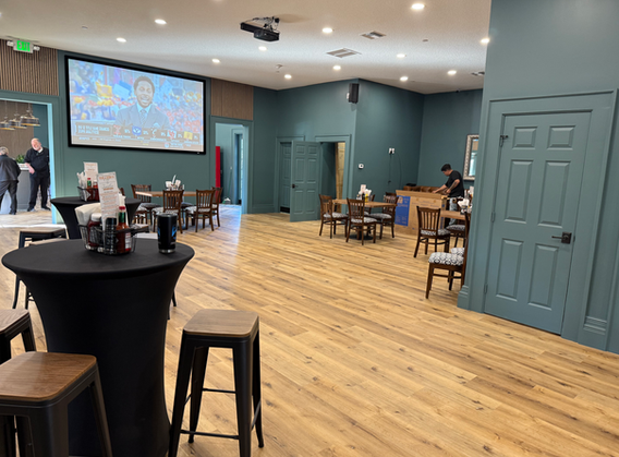 Empty dining room with tables, a screen and a waiter preparing food.