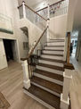 Wooden staircase with black railings leading upstairs in a modern home.