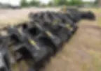 Rows of black heavy equipment grapples in an outdoor lot