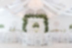 White venue with sparkly chandeliers and centerpiece of flowers white