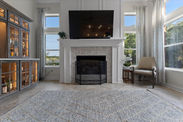 Living room with TV, fireplace, windows, rug, chair, and beautiful interior design.
