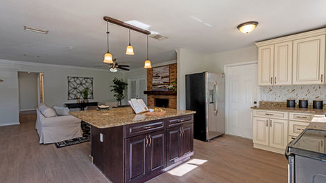 Open kitchen with island, cabinets, and appliances connected to living room space.