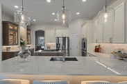 Modern kitchen with overhead lights, stainless steel appliances, and marble countertop.