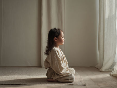Child sitting still in soft morning light, eyes closed, cream interior