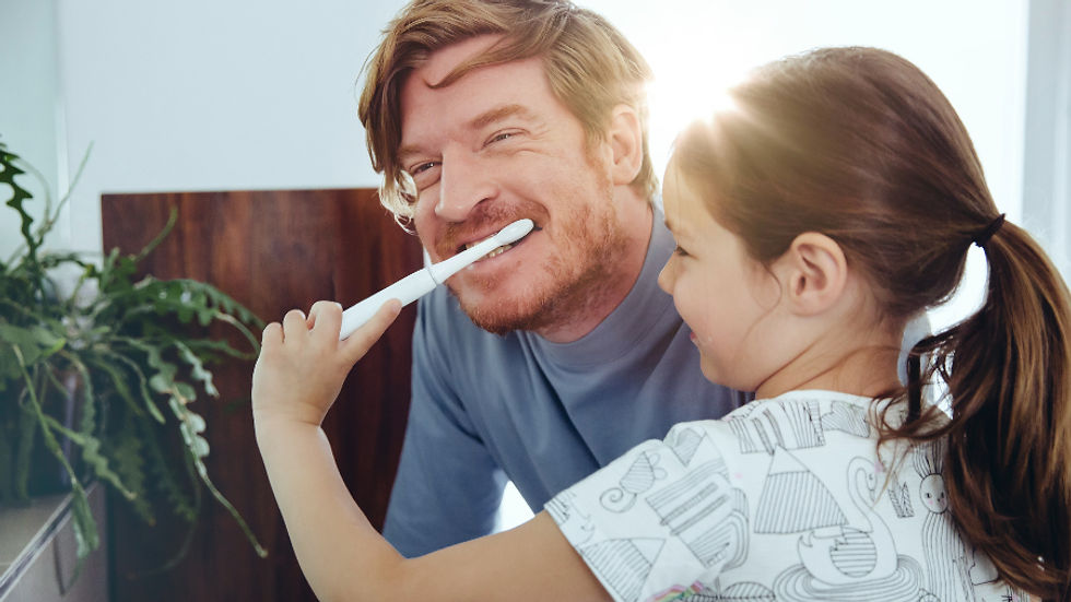 Niña cepilla los dientes a su papá. Cambios de hábitos
