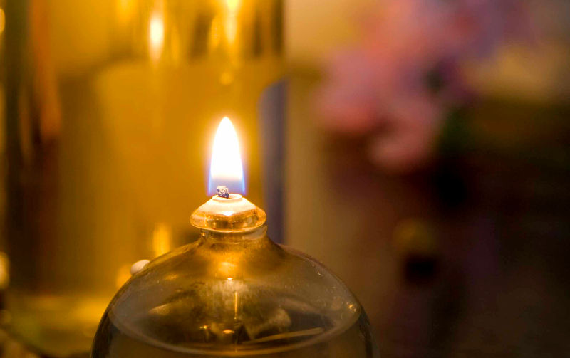 Vela encendida en un ambiente cálido y tenue. Fondo borroso con tonos dorados y rosas, creando una atmósfera tranquila y acogedora.