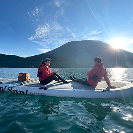 SUPに乗り湖上で飲み物を飲む2人