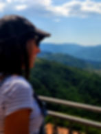 Katerina Jayamohan in a cap overlooking forested hills