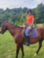Katerina Jayamohan riding a brown horse in a field.