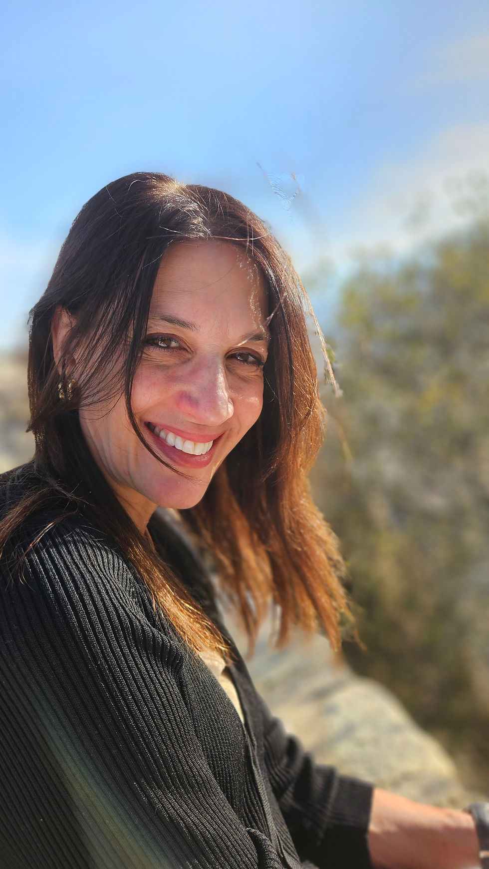 Katerina Jayamohan smiling outdoors against a blurred nature background.