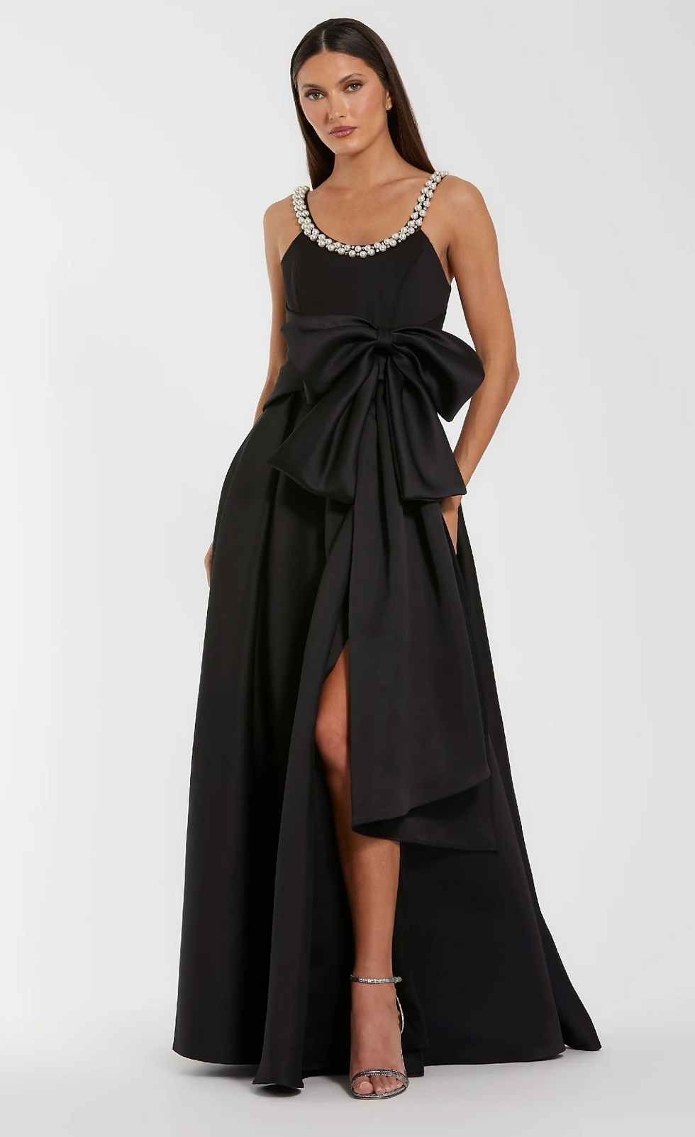 Elegant woman in a black gown with large bow and embellished straps.