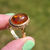 Thumbnail: a vintage 18ct yellow gold ring with rope detailing around a large bezel set amber cabochon