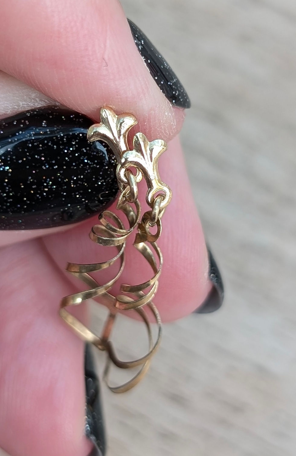 Thumbnail: yellow gold earrings with a fleur de lys stud with swirling twists of gold dangling down