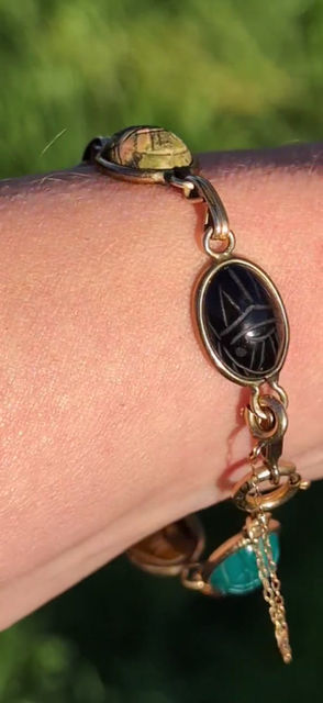 Thumbnail: A vintage yellow gold bracelet with different coloured carved gemstone scarab beetles