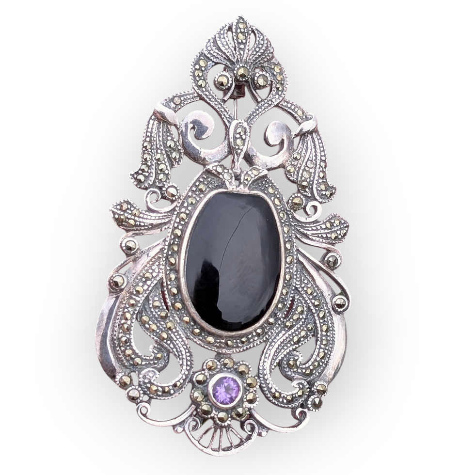 A large ornate antique silver brooch with black onyx amethyst and marcasite