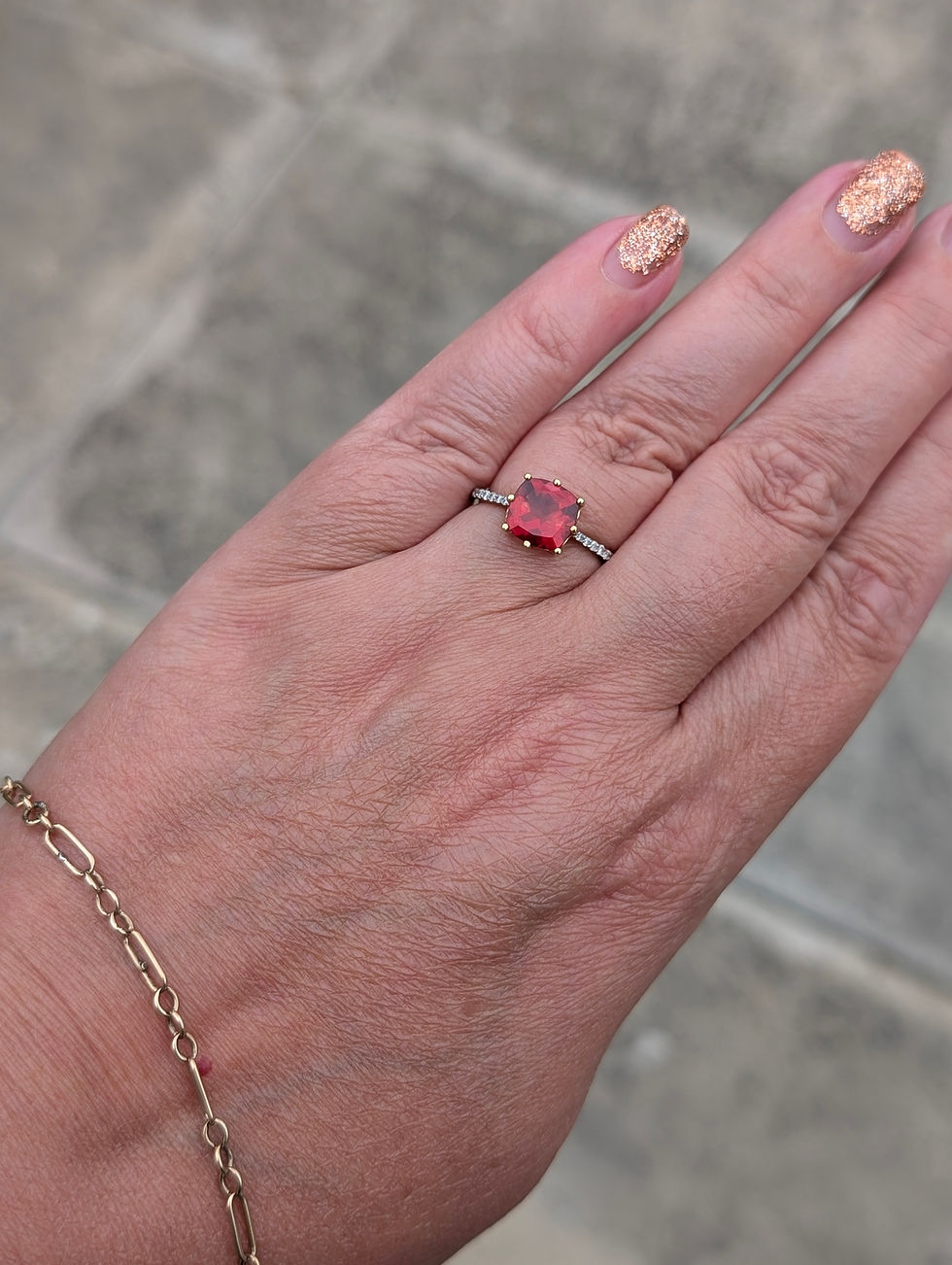 Thumbnail: yellow gold ring set with diamonds and a large cushion cut red andesine gemstone