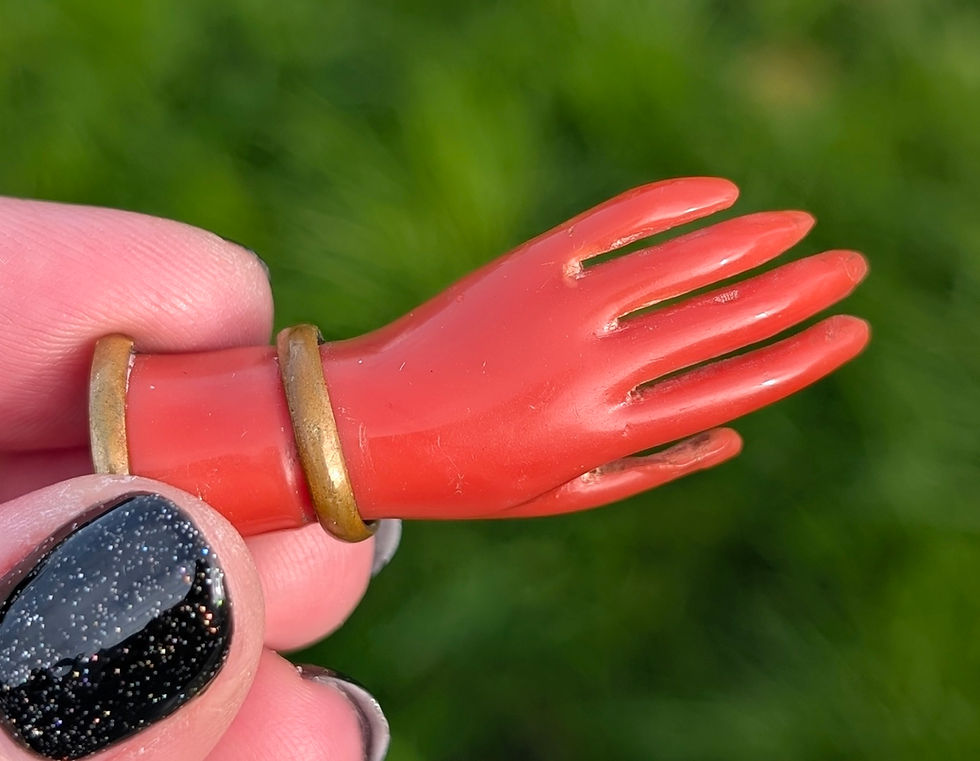 Thumbnail: A Victorian brooch of a red hand with gold bracelets